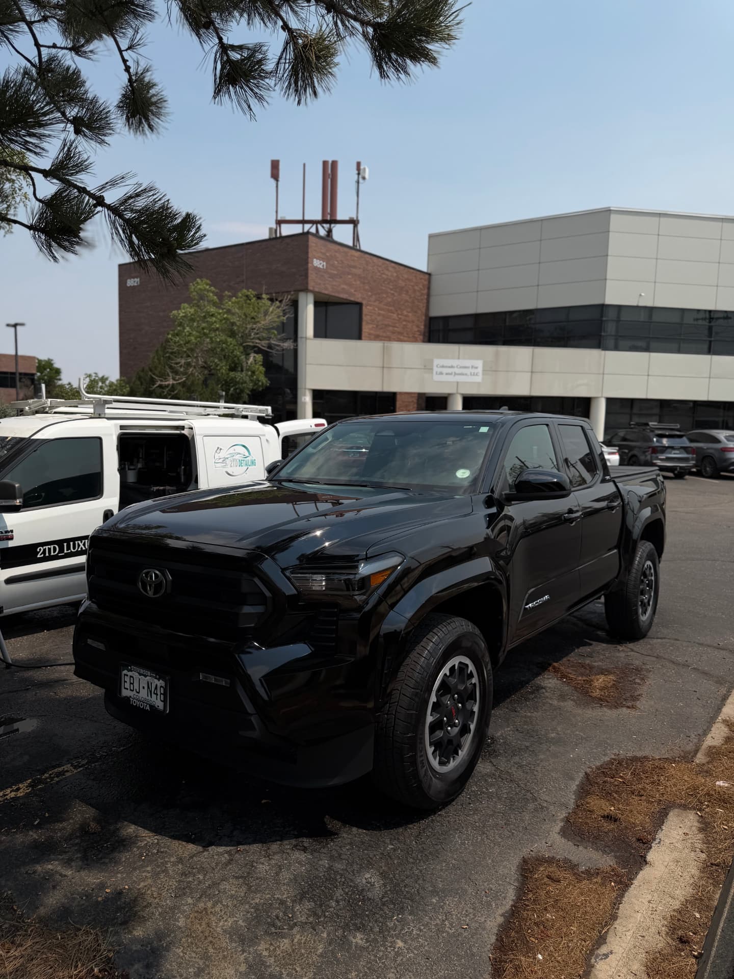 2TD mobile detailing van on-site with a customer's black Toyota Tacoma